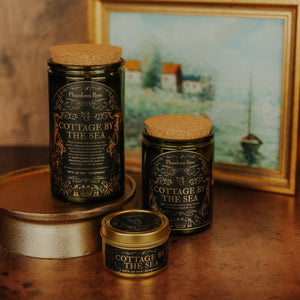 Side by side shot of the three sizes of Cottage by the Sea soy candles – 15 oz jar, 11 oz jar, and 3.3 oz gold tin.