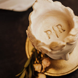 Top view of concrete goddess bust statue. The Phantom Row monogram logo with the letters P and R with a dagger icon in the middle of the letters is imprinted on top of crown where candle goes.
