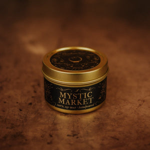 Front shot of Mystic Market 3.3 oz soy candle in a gold tin with top and black and gold foil labels with vintage illustrations on the front and lid.