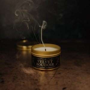 Smoke rises from an extinguished wick of a Velvet Boudoir gold tin soy candle.