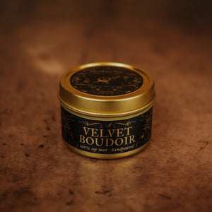 Front shot of Velvet Boudoir 3.3 oz soy candle in a gold tin with top and black and gold foil labels with vintage illustrations on the front and lid.
