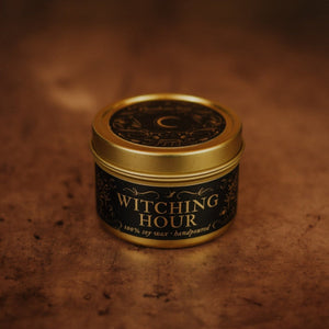 Front shot of Witching Hour 3.3 oz soy candle in a gold tin with top and black and gold foil labels with vintage illustrations on the front and lid.